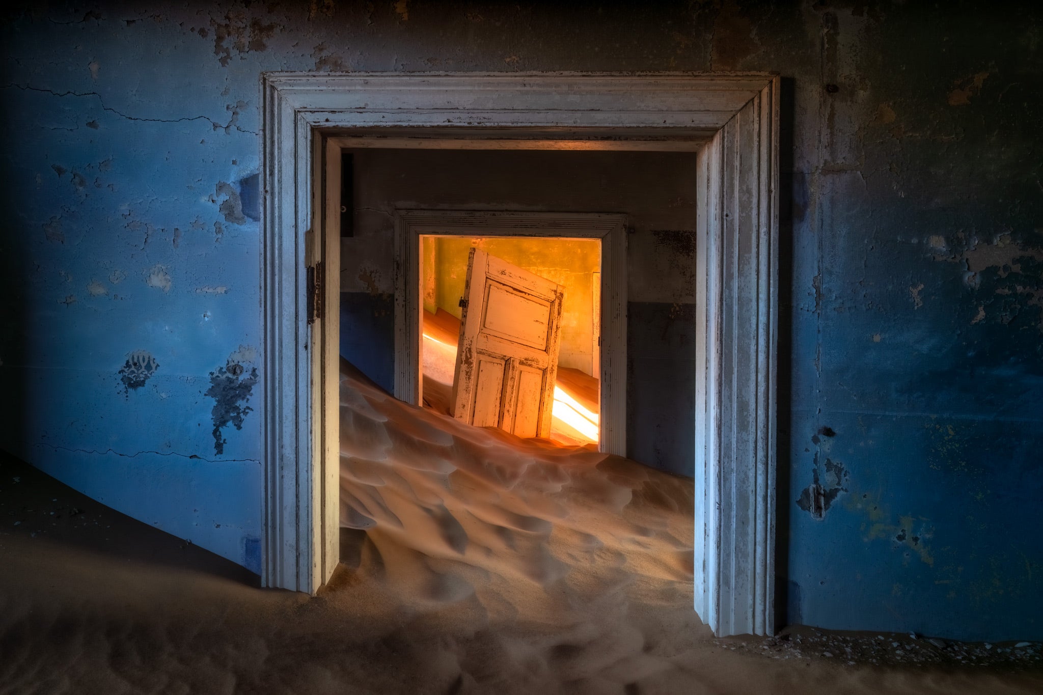 Doorway leading into a room with sand inside, suggesting an abandoned building.
