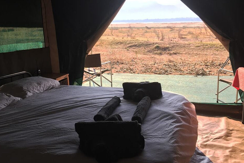 Bed inside a tent with a view of an open landscape